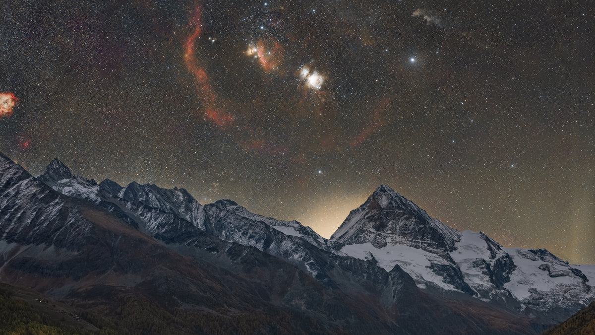 Dent Blanche enneigée au centre d’un panorama alpin, sous les étoiles et les nébulosités de la Voie lactée d’hiver.