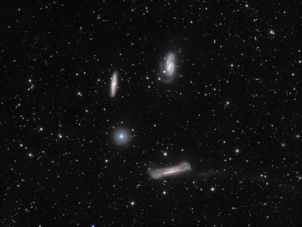 Trois galaxies du triplet du Lion dans un champ d’étoiles, dont une longue galaxie vue par la tranche.