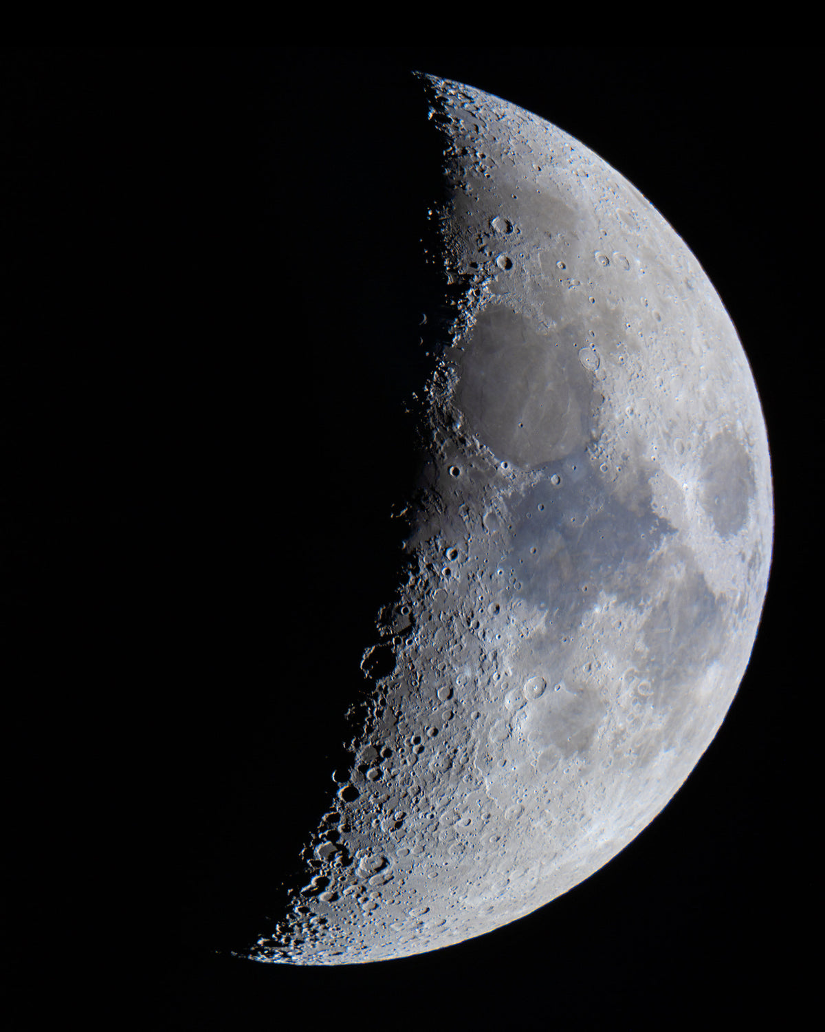 Moitié droite éclairée du disque lunaire, avec des cratères visibles près de la limite de l’ombre.