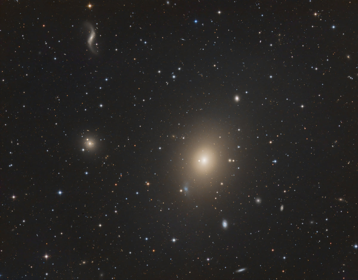 Galaxie Messier 49 sous la forme d’une lueur ovale dorée au centre plus brillant, parmi les étoiles.