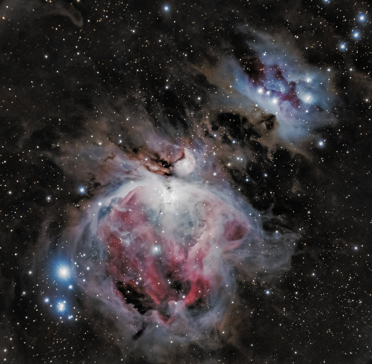 Nébuleuse d’Orion au cœur blanc brillant, entouré de nuages roses et bleutés et de filaments sombres.