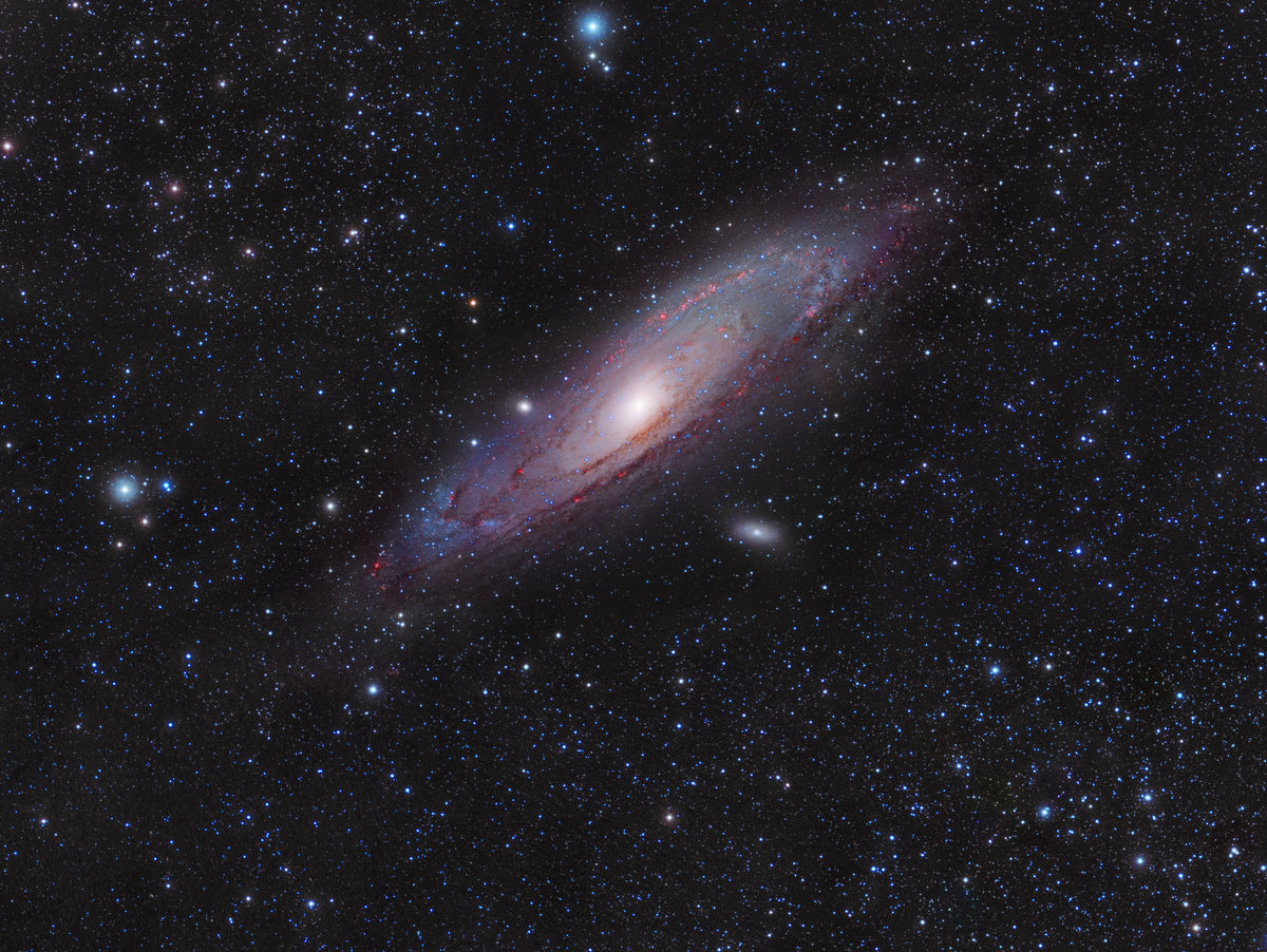 Galaxie d’Andromède en diagonale, avec un centre brillant et des bandes sombres dans son disque allongé.