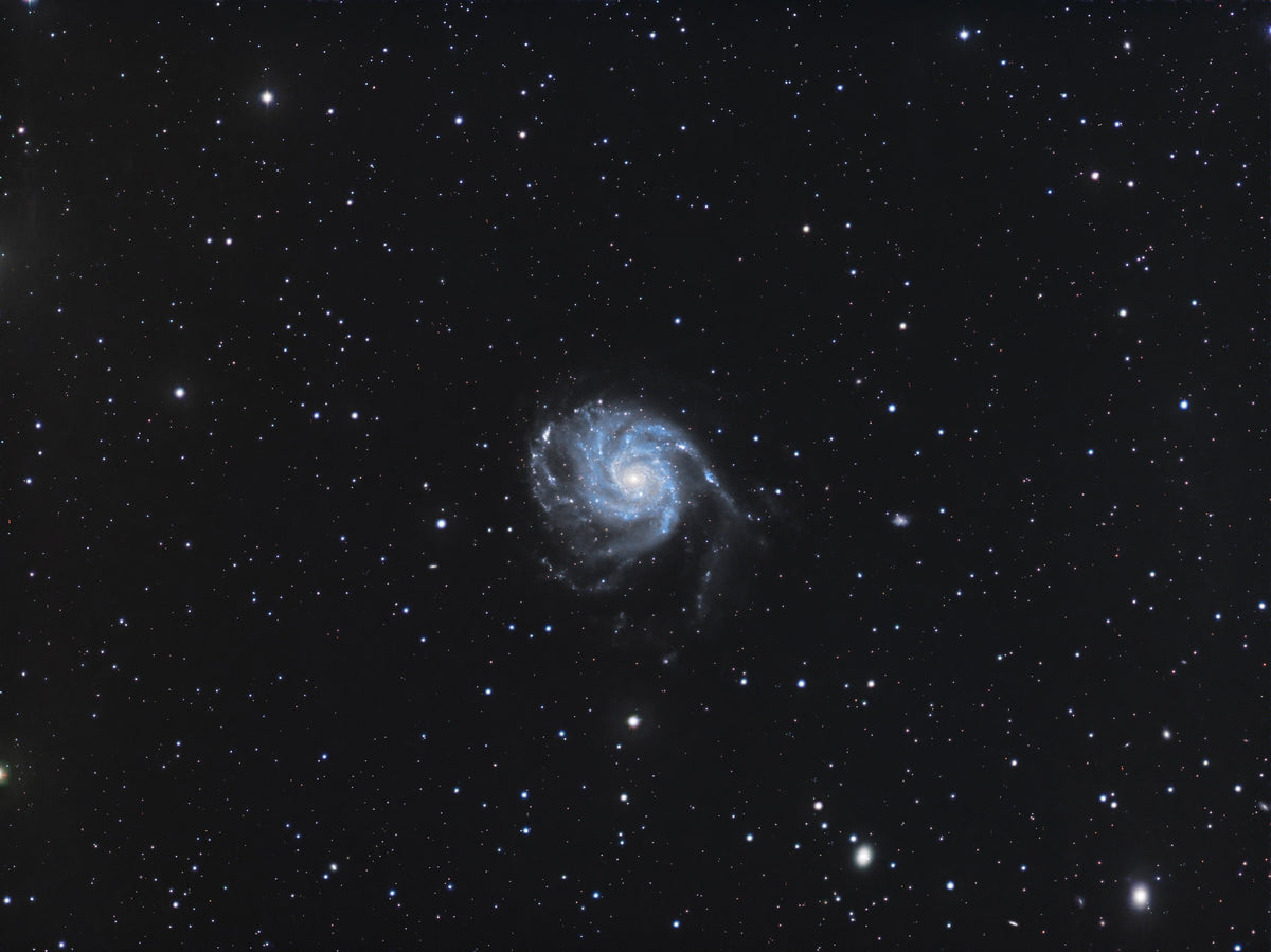 Galaxie du Moulinet aux bras spiraux bleutés entourant un noyau clair, sur fond d’étoiles.