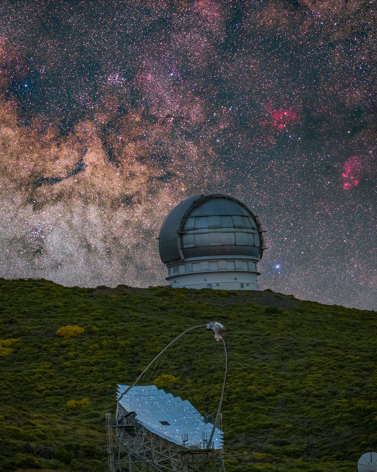 Coupole du GTC et miroir segmenté d’un télescope MAGIC sur une pente végétalisée, sous un ciel très dense en étoiles.