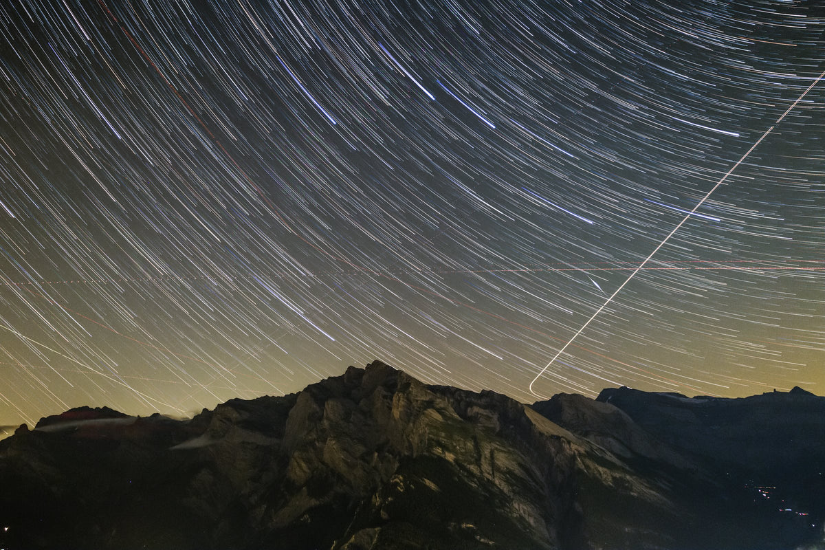 Longues traces d’étoiles courbées au-dessus d’une chaîne de montagnes sombre dominée par le Haut de Cry.