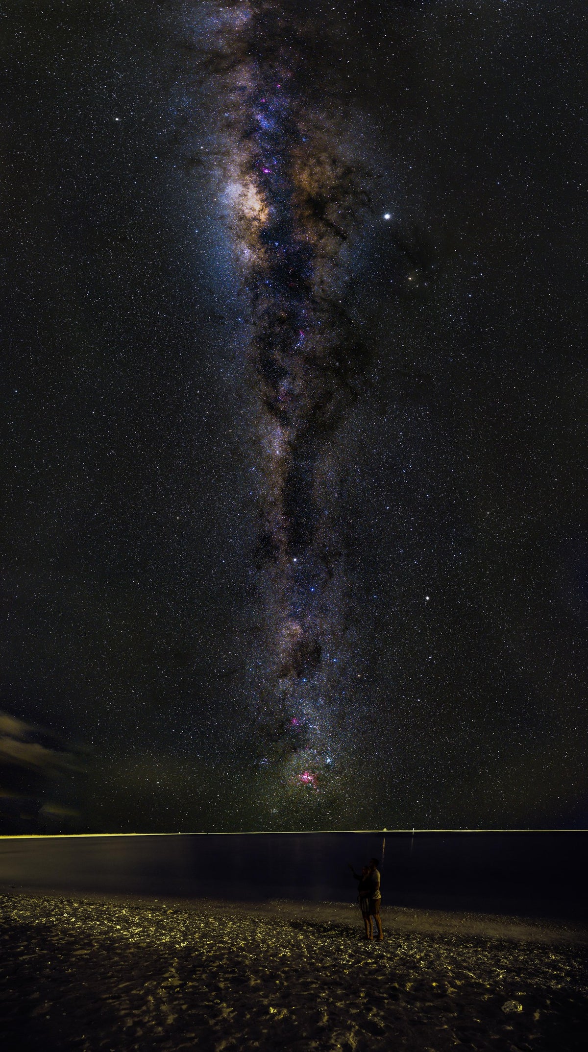 Bande verticale de la Voie lactée dans un ciel noir étoilé, au-dessus d’un paysage côtier de La Réunion.