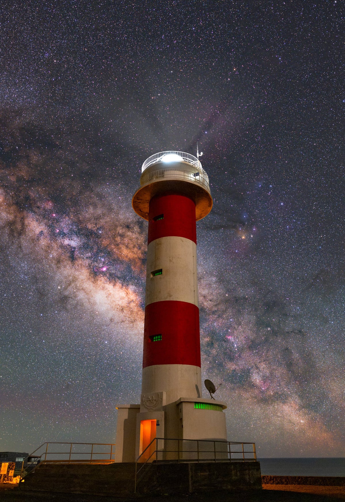 Phare rouge et blanc de Fuencaliente au premier plan, devant la bande étoilée de la Voie lactée.